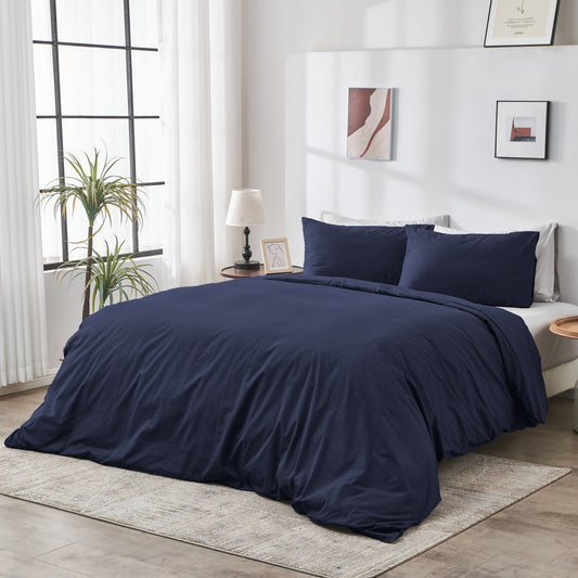 Navy blue bedding set on a bed in a well-lit bedroom with decor elements.