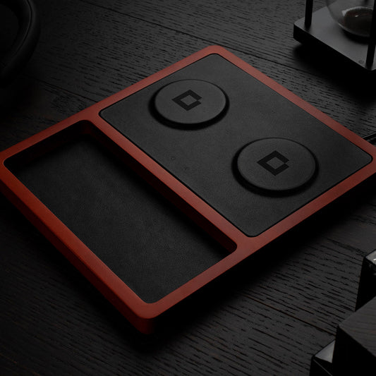 A black and oak wood 2-in-1 MagSafe wireless charging pad with a smartphone and earbuds being charged on it.