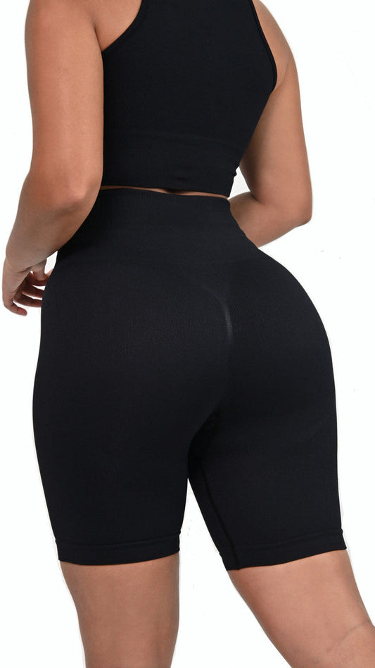 Black athletic outfit with a crop top and high-waisted shorts on a white background