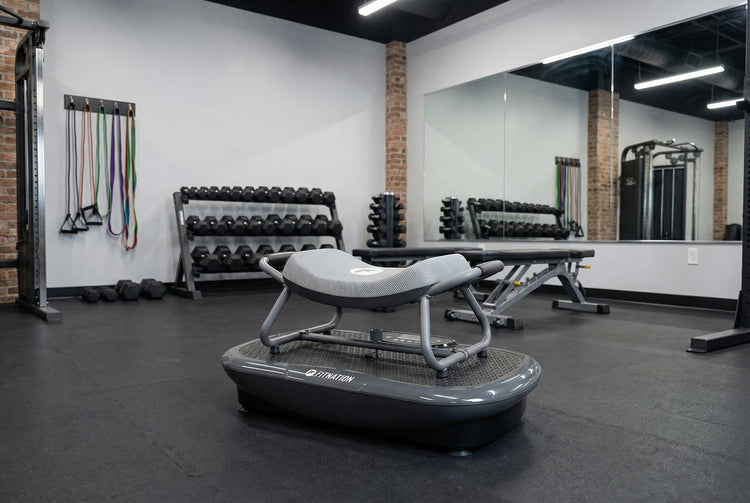Gym interior with exercise equipment including a vibration plate, dumbbells, and resistance bands.
