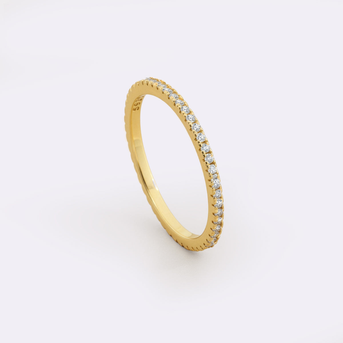 Gold ring with embedded diamonds on a light gray background
