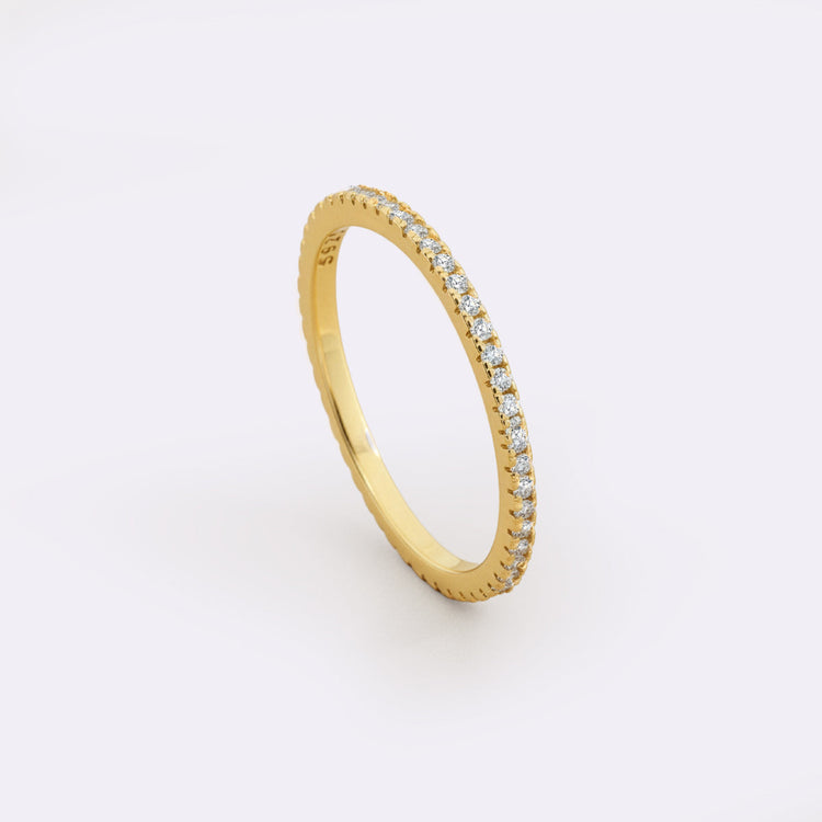 Gold ring with embedded diamonds on a light gray background