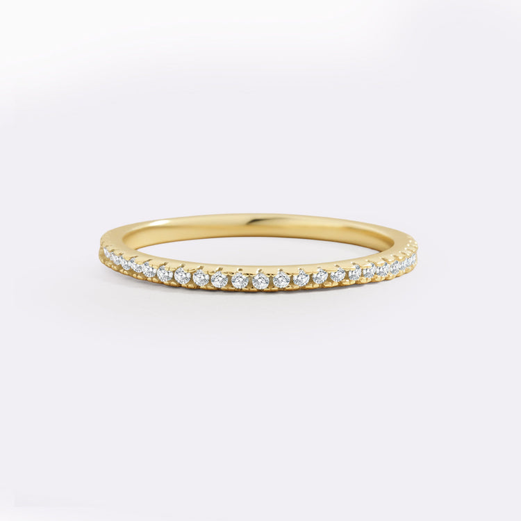Gold ring with small diamonds on a light gray background