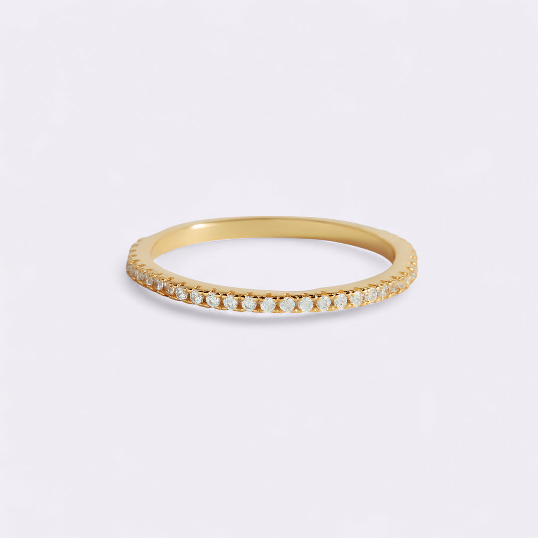 Gold ring with small diamonds on a light gray background