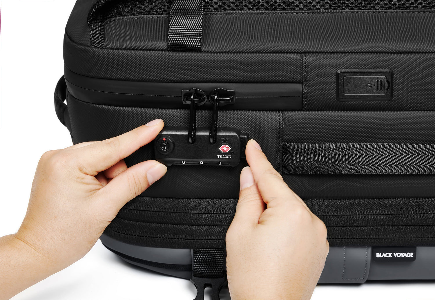 Person attaching a suitcase tag to a black suitcase