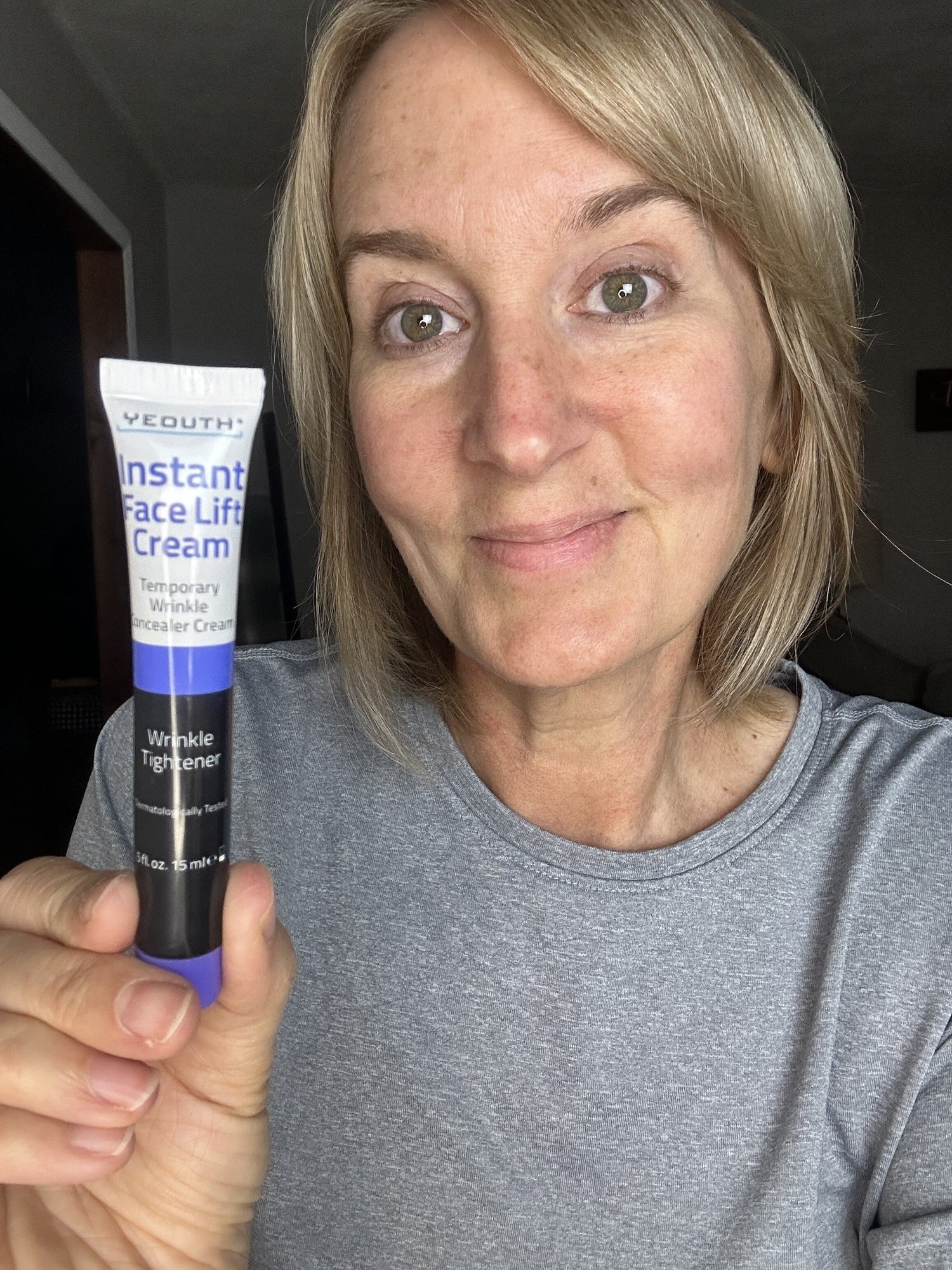 Woman holding a tube of Vothic Instant Face Lift Cream in a casual setting.