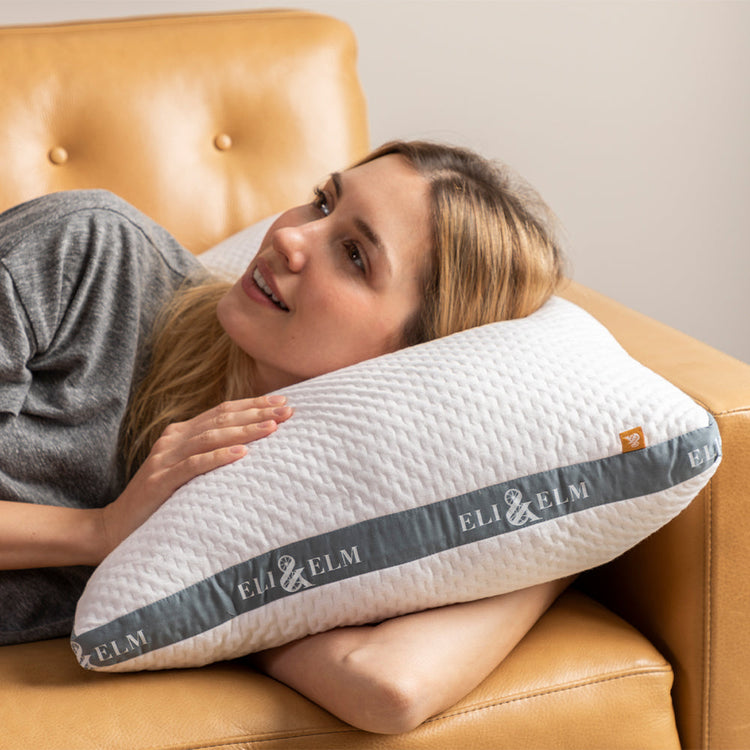 A person resting on a side sleeper pillow with the brand name 'ELI & ELM' visible on the pillowcase.