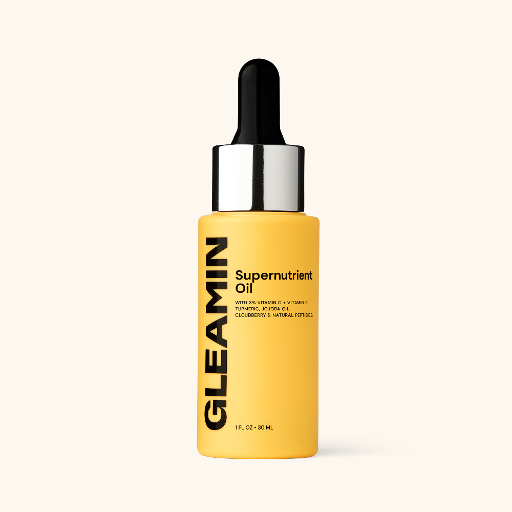 Yellow bottle of GLEAMIN Supernutrient Oil with a dropper on a white background