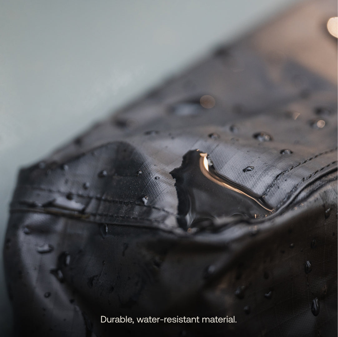 Close-up of water droplets beading on the surface of the Luno® Gear & Shoe Storage Bag, highlighting its durable, water-resistant material. Text at bottom: "Durable, water-resistant material.