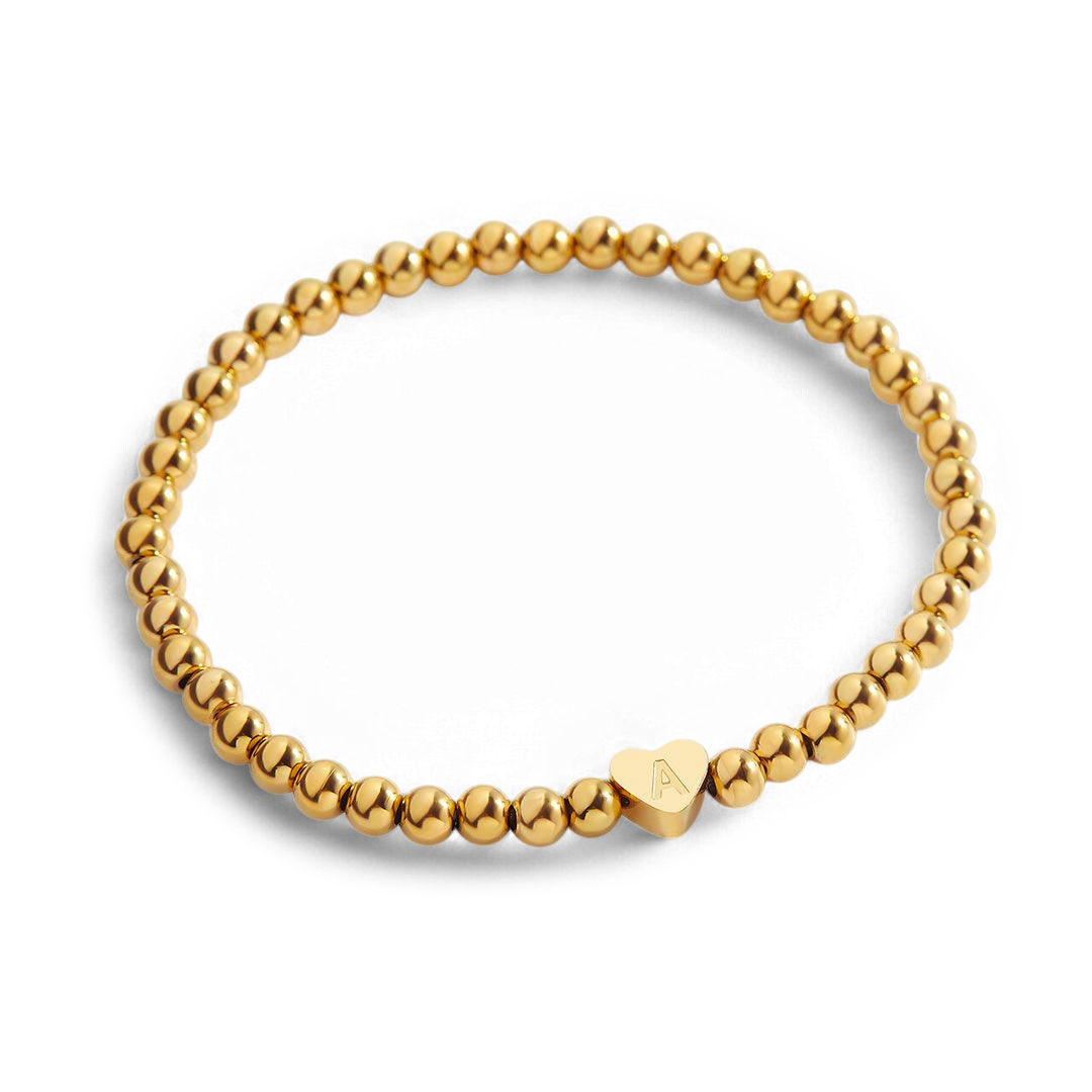 Gold beaded bracelet with a heart-shaped clasp on a white background