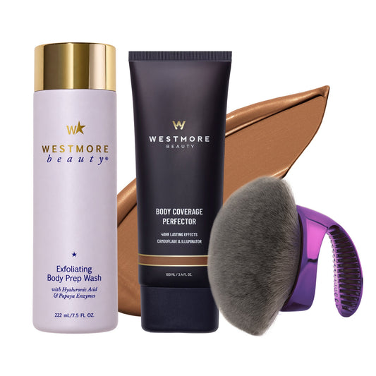 Westmore Beauty hair and skin care set featuring Exfoliating Body Prep Wash in a lavender bottle with a gold cap, Body Coverage Perfector in a dark navy tube with a gold band, a large brown makeup swatch, a gray makeup brush, and a purple-handled brush attachment, all on a white background.