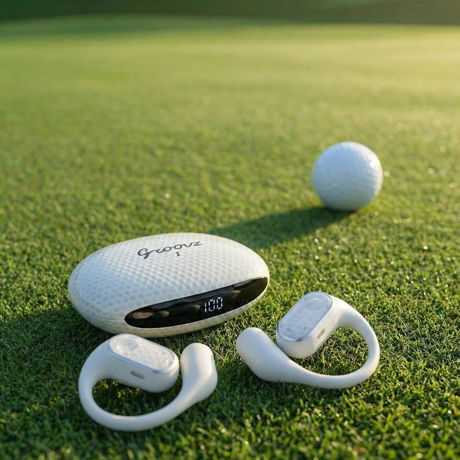 White electronic device with 'Groove' branding on a grassy field with a golf ball.