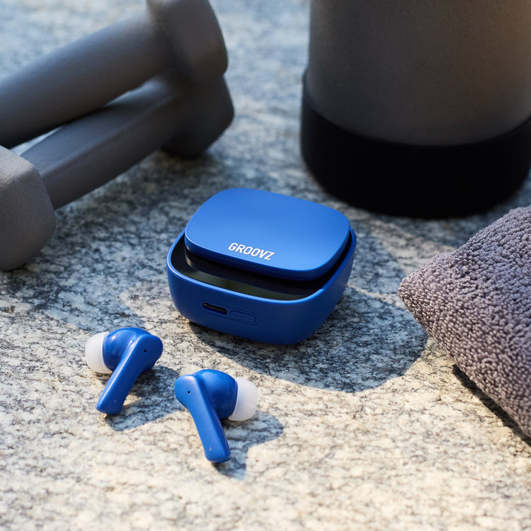 Blue wireless earbuds with charging case on a textured surface