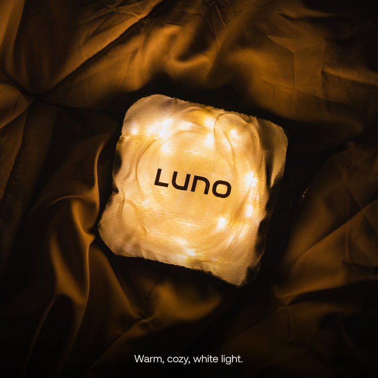 Lighted cube with 'Luno' branding on a dark fabric background