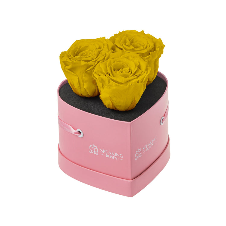 Pink heart-shaped box with yellow roses on a white background