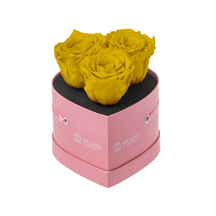 Pink heart-shaped box with yellow roses on a white background