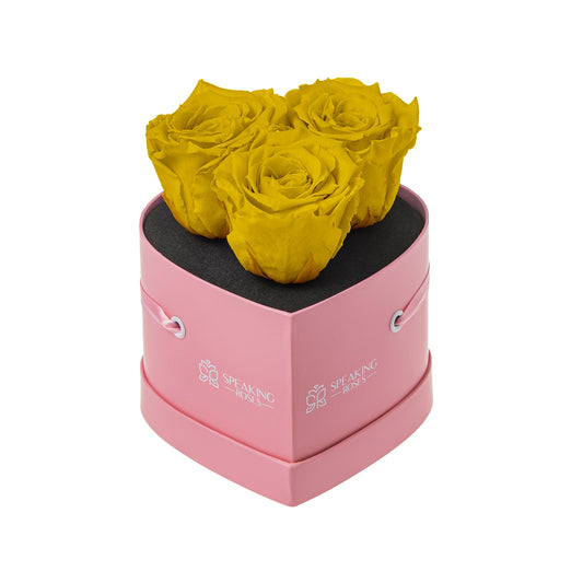 Pink heart-shaped box with yellow roses on a white background
