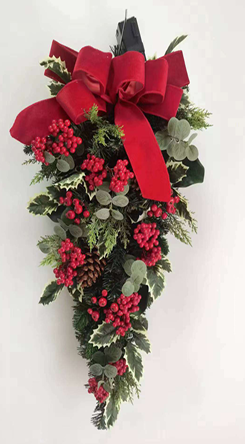 Christmas wreath with red berries, greenery, and a large red bow on a white background