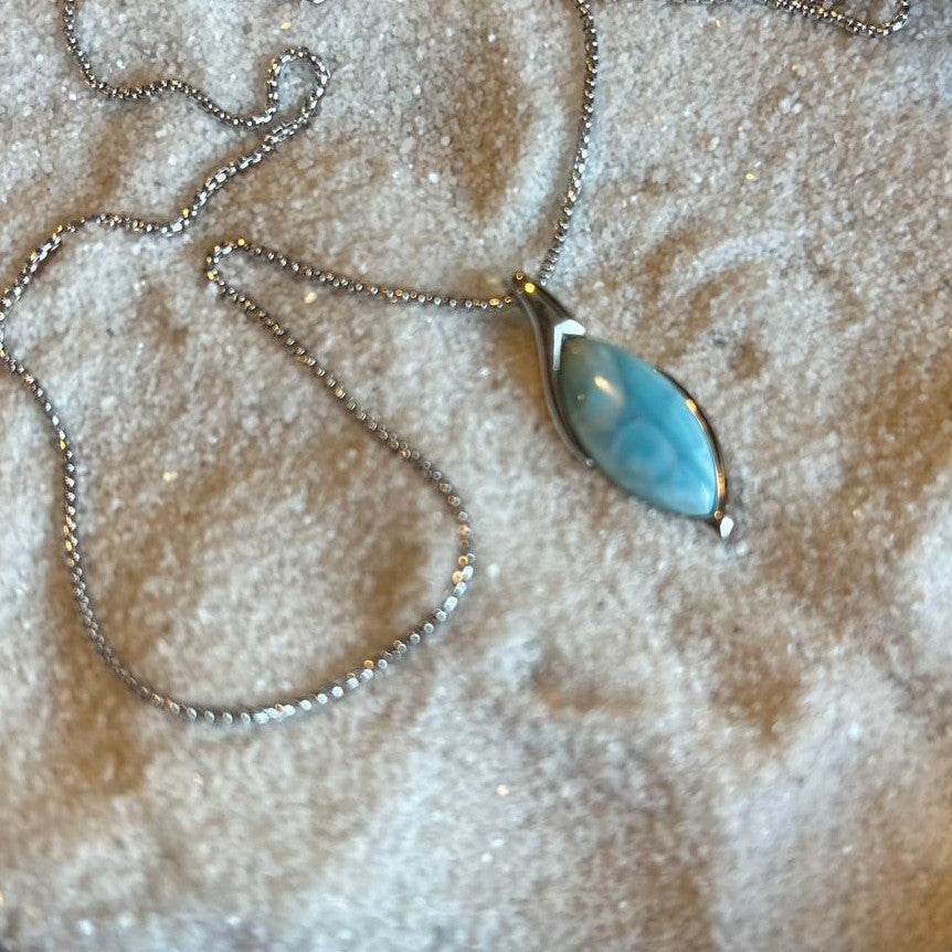 Necklace with a blue pendant on a textured beige surface