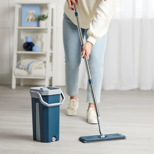 Person cleaning a floor with a mop and bucket in a room.