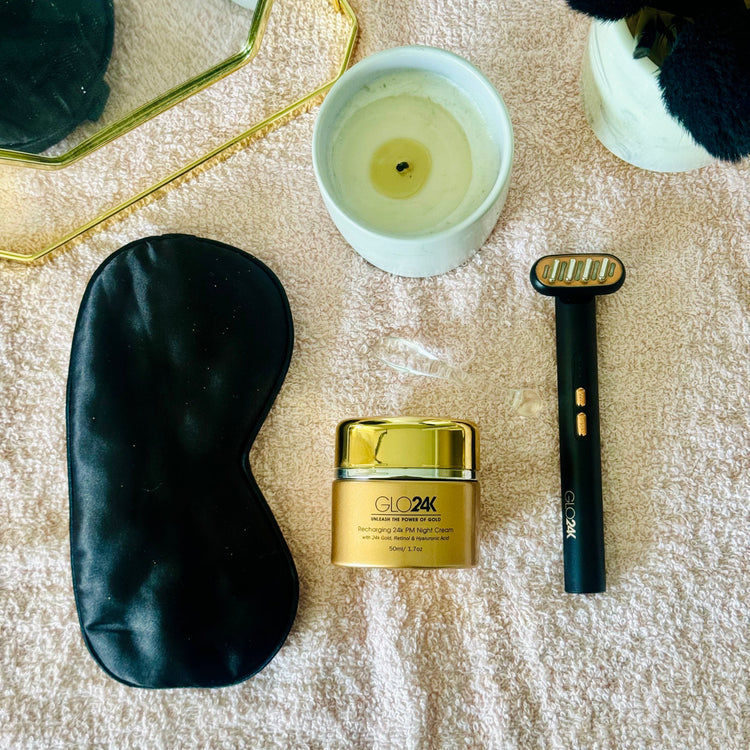 Glowing cream, black eye mask, and black device on a textured surface with a candle.