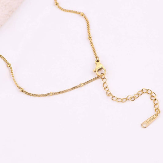 Gold necklace with a heart-shaped pendant on a white background