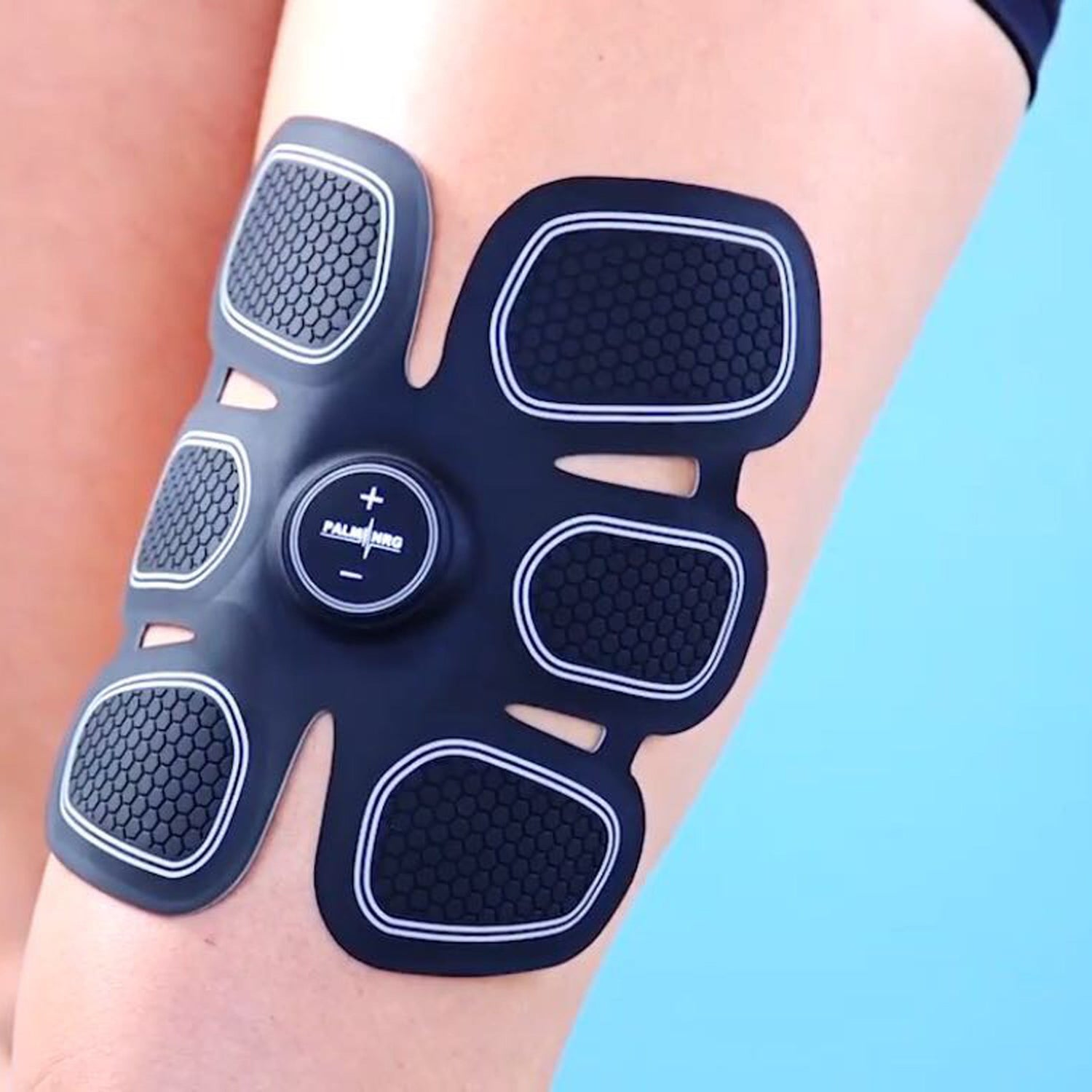 Electromagnetic muscle stimulator on a person's leg against a blue background