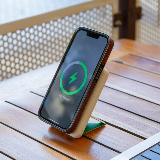 A white NYTSTND Pulse Power Bank with a green circle indicating the magnetic charging area, featuring an adjustable kickstand.