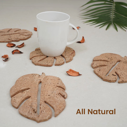 Set of leaf-shaped coasters with a glass of dark liquid on a white background