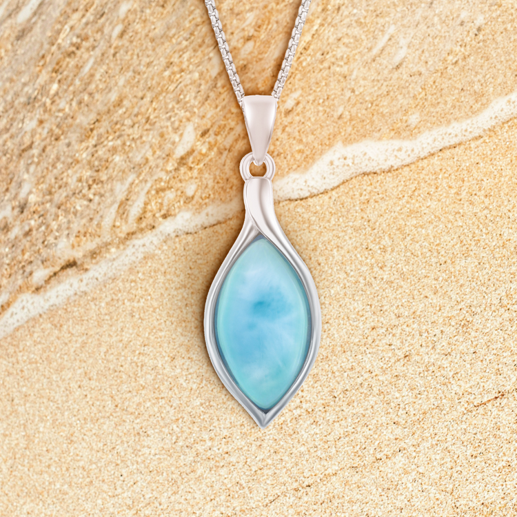 Silver pendant with a blue stone on a sandy background