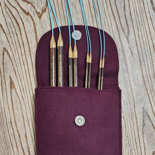 Set of adjustable knitting needles with a purple case and label on a white background
