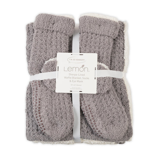 Gray textured blanket, socks, and eye mask set with Lemon label on a white background