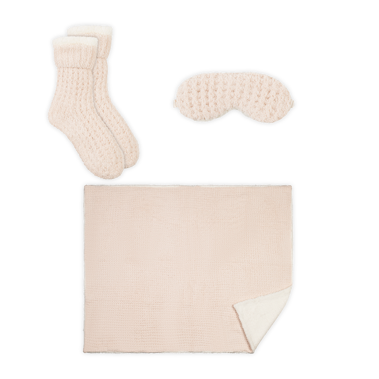 Set of cream-colored knitted socks and eye mask on a white background