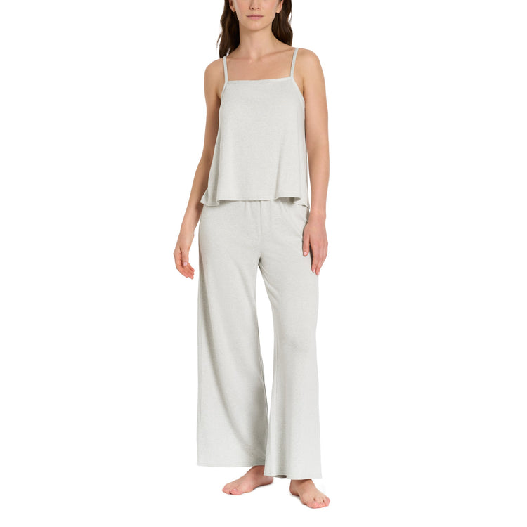 Woman wearing a light gray sleeveless top and wide-leg pants on a white background