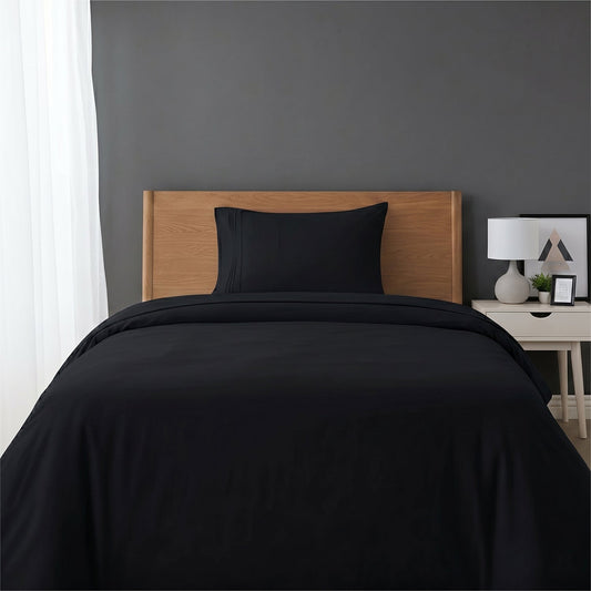 Red bedspread on a wooden bed with a white nightstand and decor items in the background.