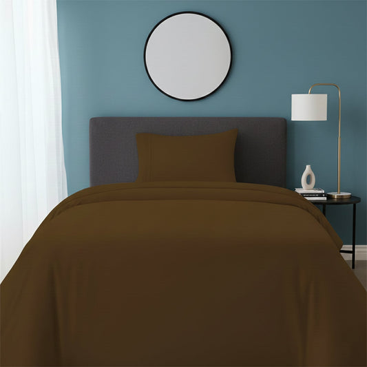 Red bedspread on a wooden bed with a white nightstand and decor items in the background.