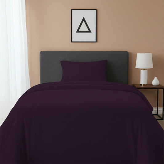 Red bedspread on a wooden bed with a white nightstand and decor items in the background.