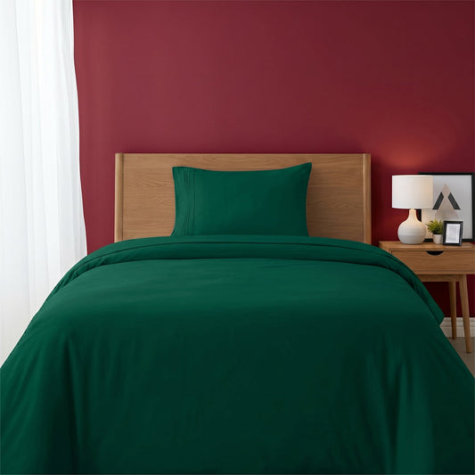 Red bedspread on a wooden bed with a white nightstand and decor items in the background.
