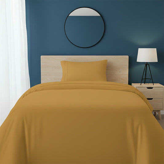 Red bedspread on a wooden bed with a white nightstand and decor items in the background.
