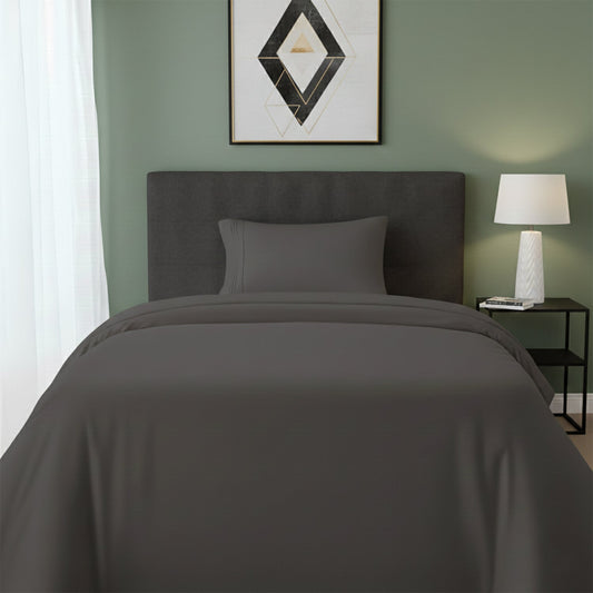 Red bedspread on a wooden bed with a white nightstand and decor items in the background.