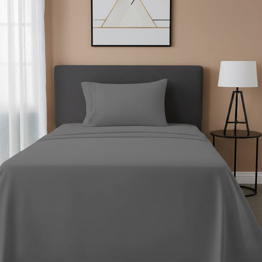 Red bedspread on a wooden bed with a white nightstand and decor items in the background.