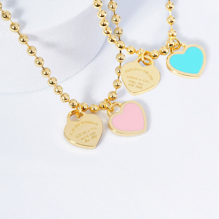 Gold beaded necklace with heart-shaped charms on a white background