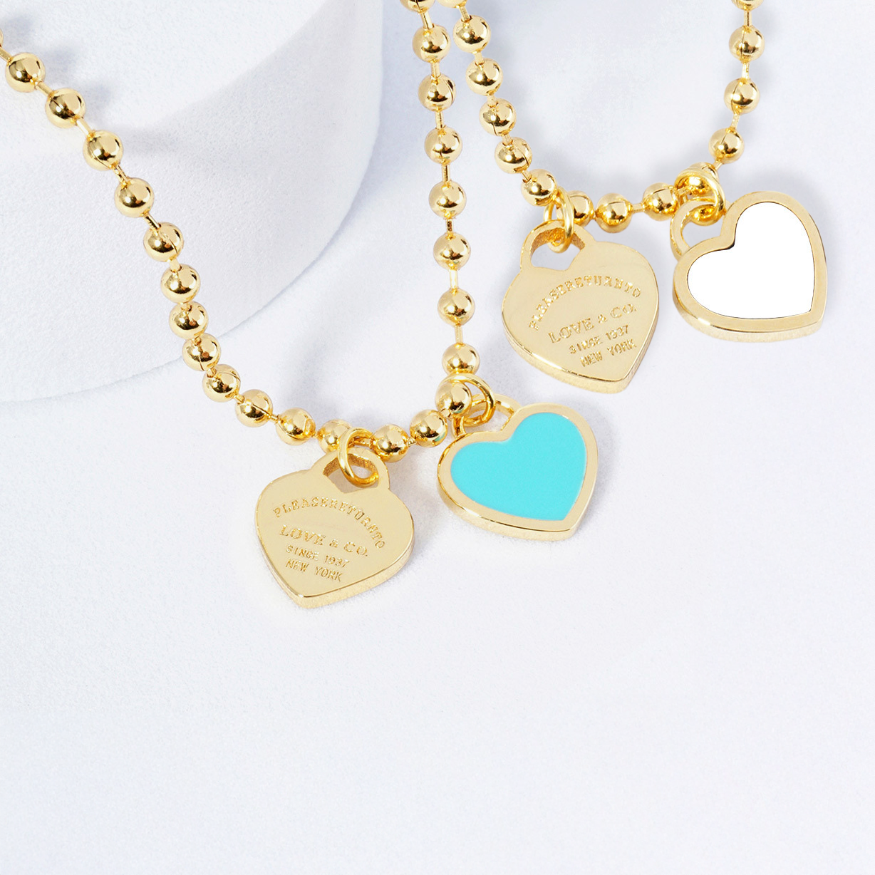 Gold necklace with heart-shaped charms on a white background