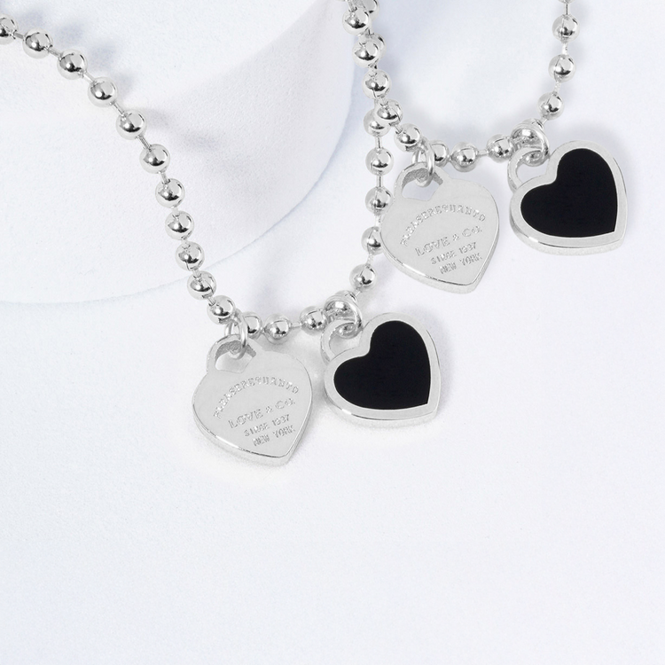 Silver necklace with heart-shaped pendants on a white background