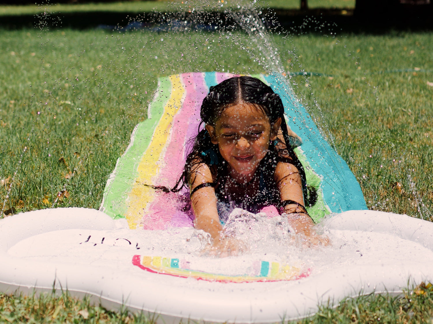 Child playing on a inflatable slide with water splashing around