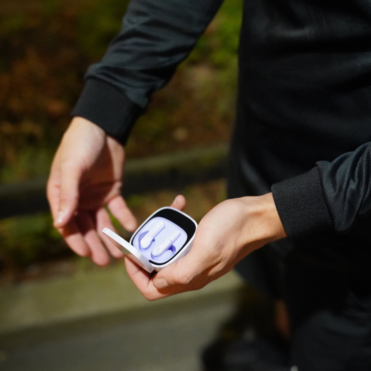 Person holding a smartphone with a blurred outdoor background