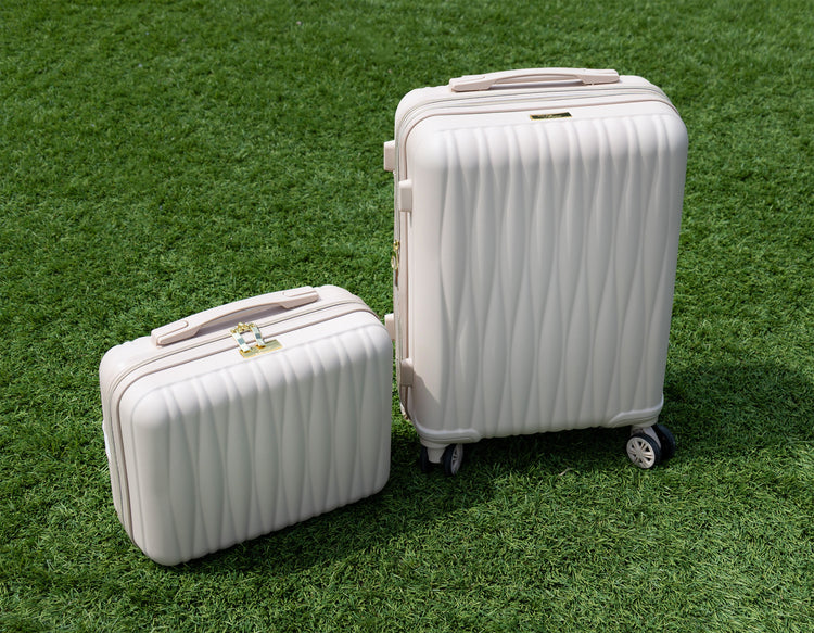 Two white suitcases on a grassy surface