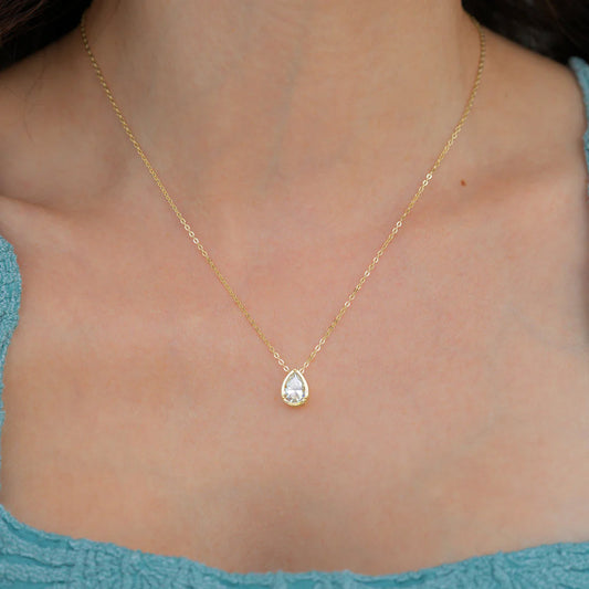 Gold necklace with a teardrop-shaped diamond pendant on a white background