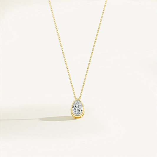 Gold necklace with a teardrop-shaped diamond pendant on a white background