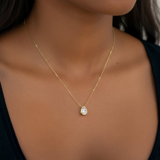 Gold necklace with a teardrop-shaped diamond pendant on a white background